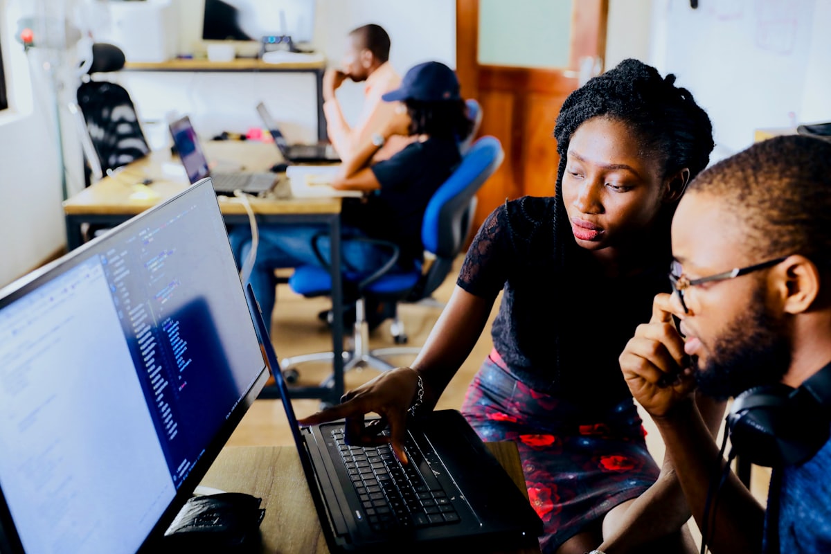 A mentor guiding a learner through code on a laptop